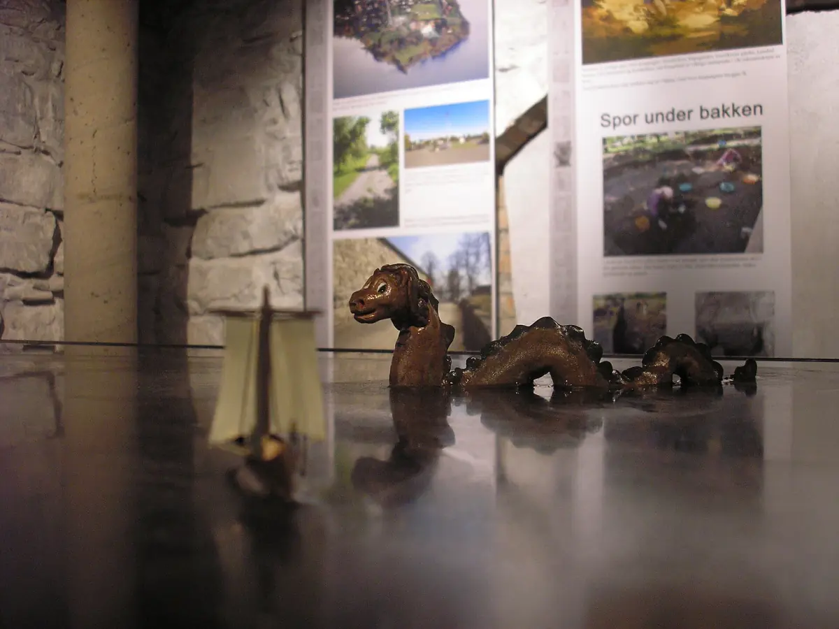 Museumsutstilling på Domkirkeodden med båtmodell og bilder bak glass