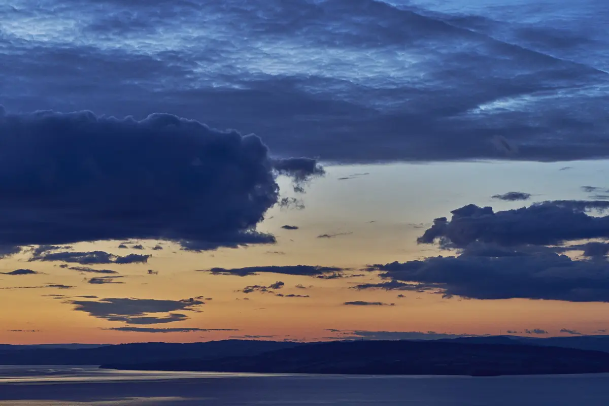 Mørkeblå skyer og oransje solnedgangsglød over Mjøsa om høsten
